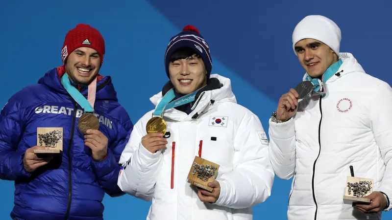 Yun Sung-bin in a white Team Korea jacket holding up his gold medal on the Olympic podium, between Dominic Parsons and Nikita Tregubov