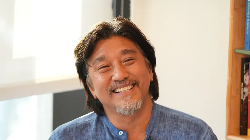 Chef Edward Lee with long dark hair and a grey beard, smiling broadly in a denim shirt